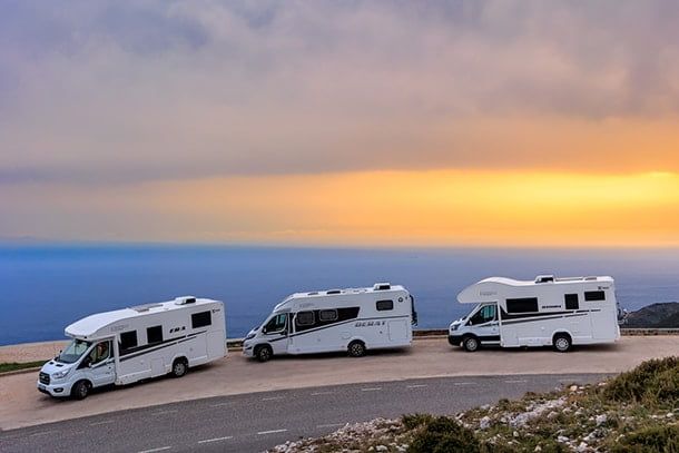 Nomad Camper's fleet parked overlooking the ocean at sunset in Albania, capturing the freedom of travel and adventure with stunning scenic views.