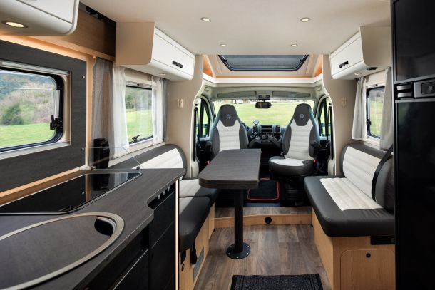 Nomad Camper's dining area in Albania, with a convertible table, comfortable seating, and a fully equipped kitchen setup, reflecting the luxurious yet practical design of a modern camper interior.