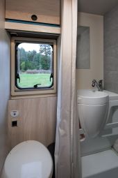Nomad Camper's compact and efficient bathroom design, featuring a toilet, sink, and shower with a view of the Albanian countryside through the window